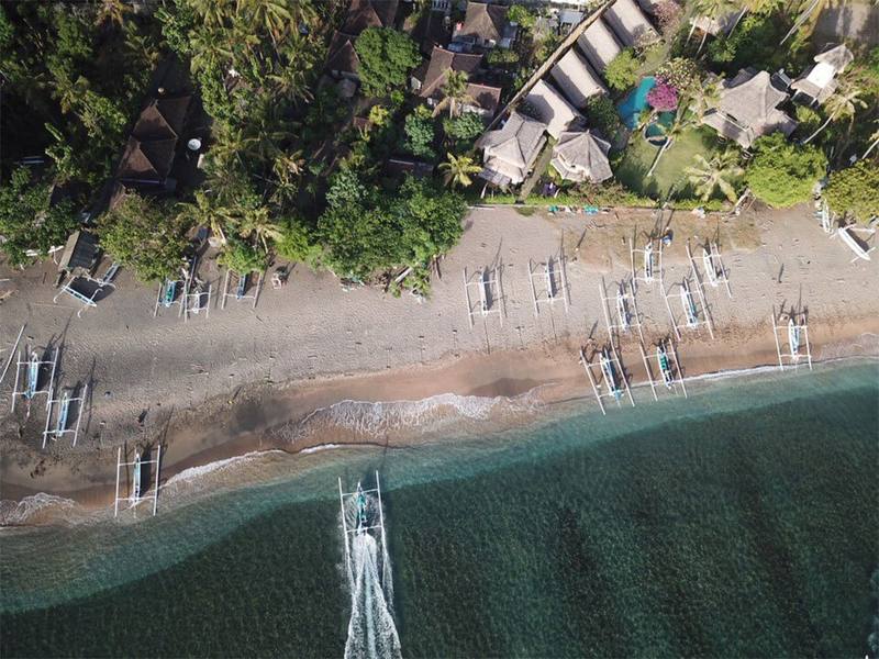 Aerial view of the beach in front of the hotel lined with traditional jukung outrigger boats