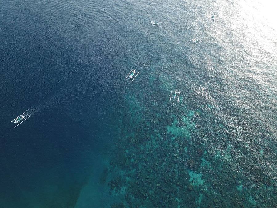 Aerial view of the turquoise reef and fishing boats in Lean bay, Amed