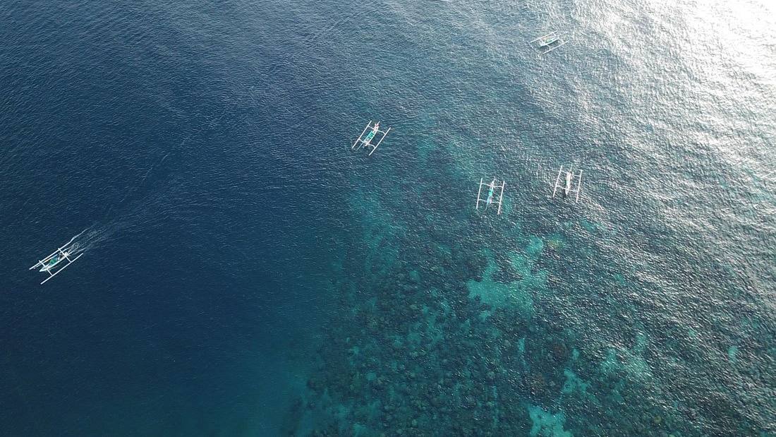 Aerial view of the turquoise reef and fishing boats in Lean bay, Amed