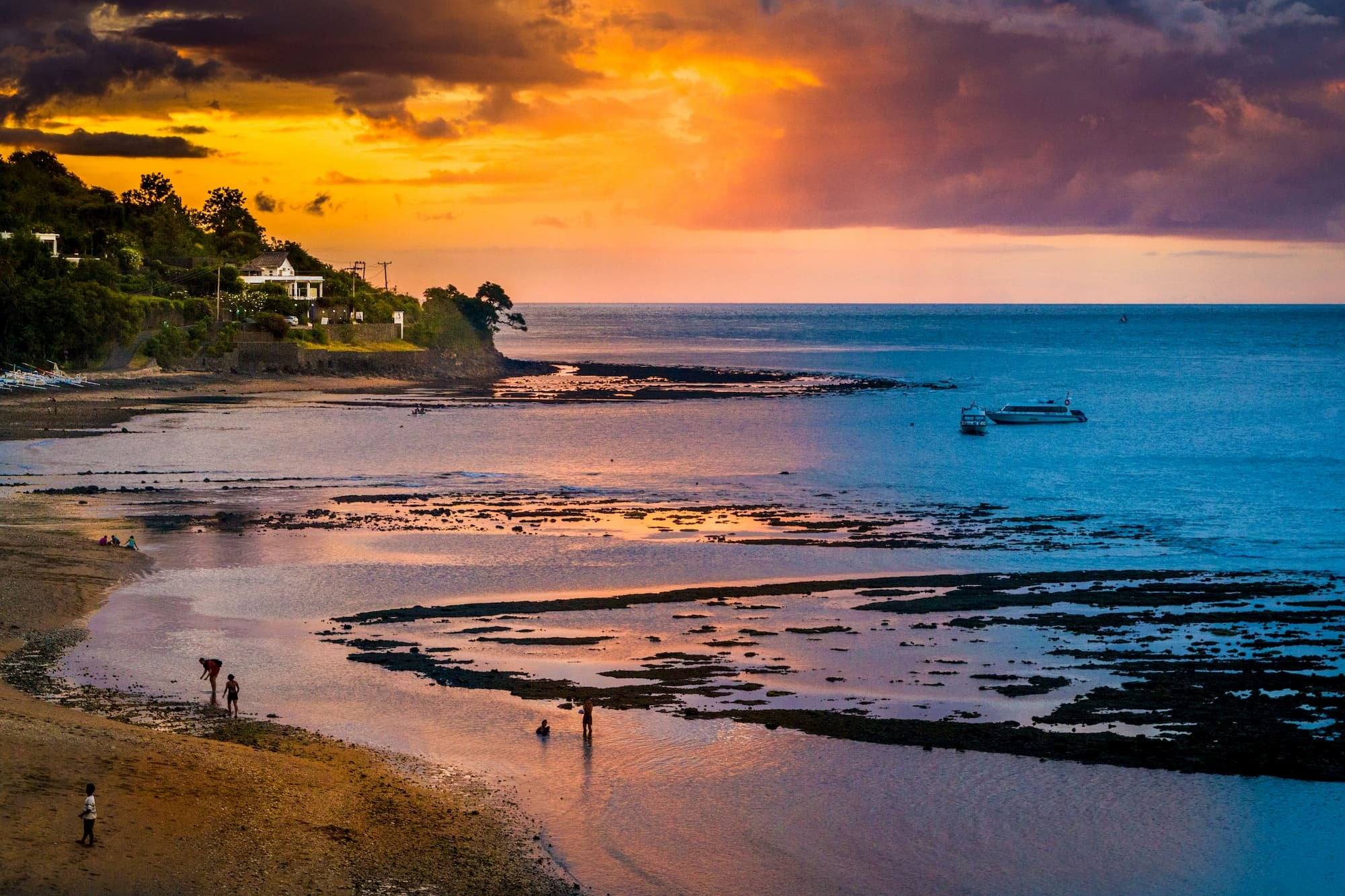 Amed coastline at dusk with the reef exposed at low tide and a golden sky