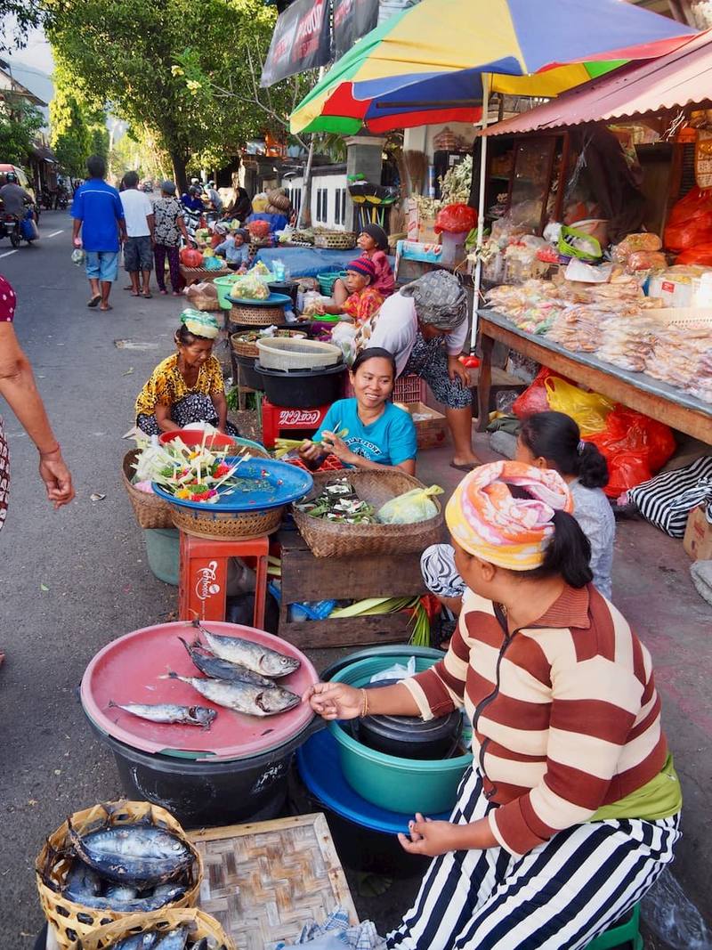 A busy traditional market in east Bali with fruit, fish and colourful parasols