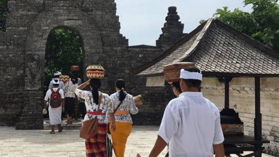 Balinese villagers in traditional dress walking to a temple ceremony