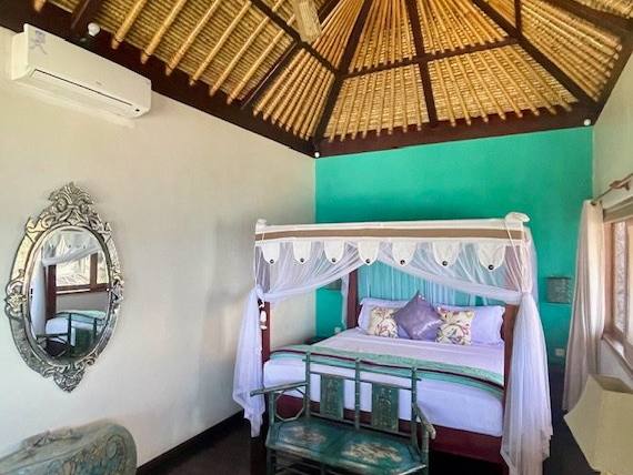 Beachfront villa bedroom with a canopy bed and turquoise wall