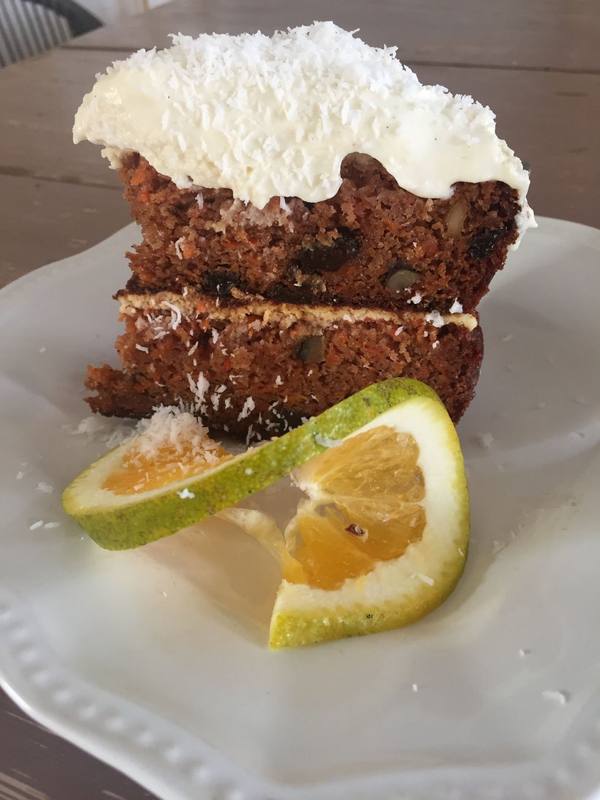 A slice of homemade cake with cream and an orange slice