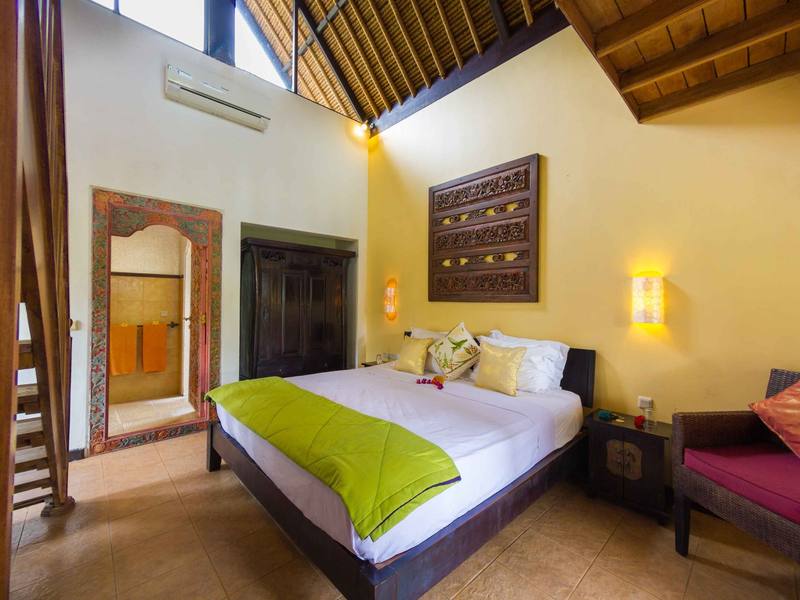 King-size bed with carved headboard art in a Beach Cottage at Life in Amed