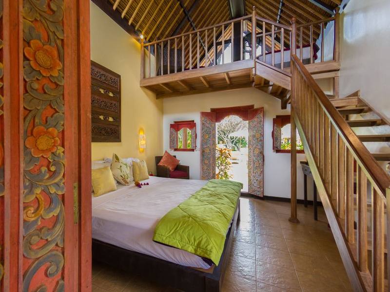 Inside a Beach Cottage: king bed, carved door and stairs to the loft