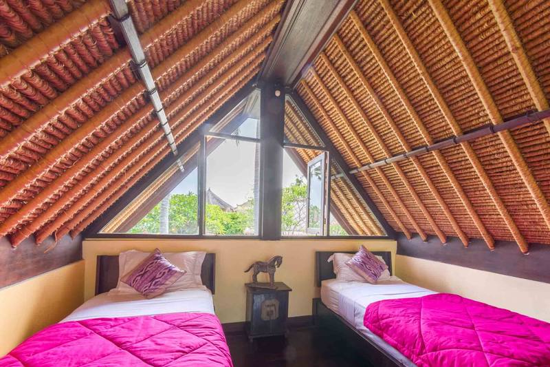Two single beds in the thatched-roof loft of a Beach Cottage