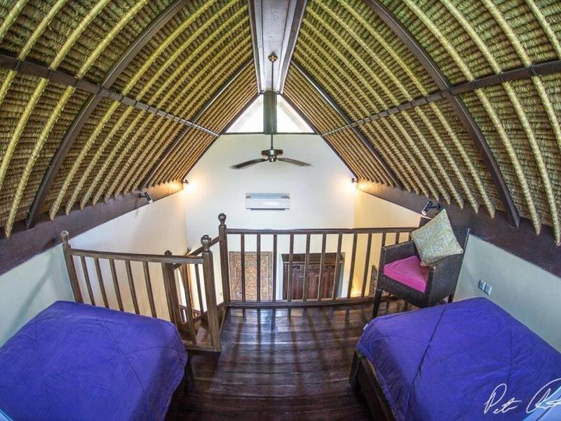 Cottage loft with two single beds under a thatched roof