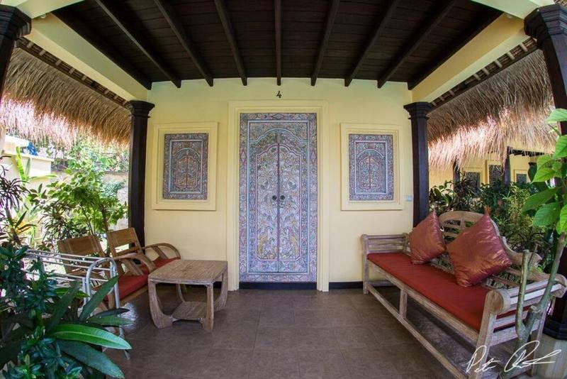 Cottage terrace with carved blue door and a daybed among plants