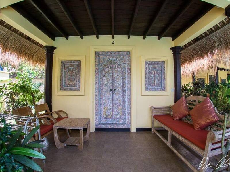 Cottage terrace with carved blue door and a daybed among plants