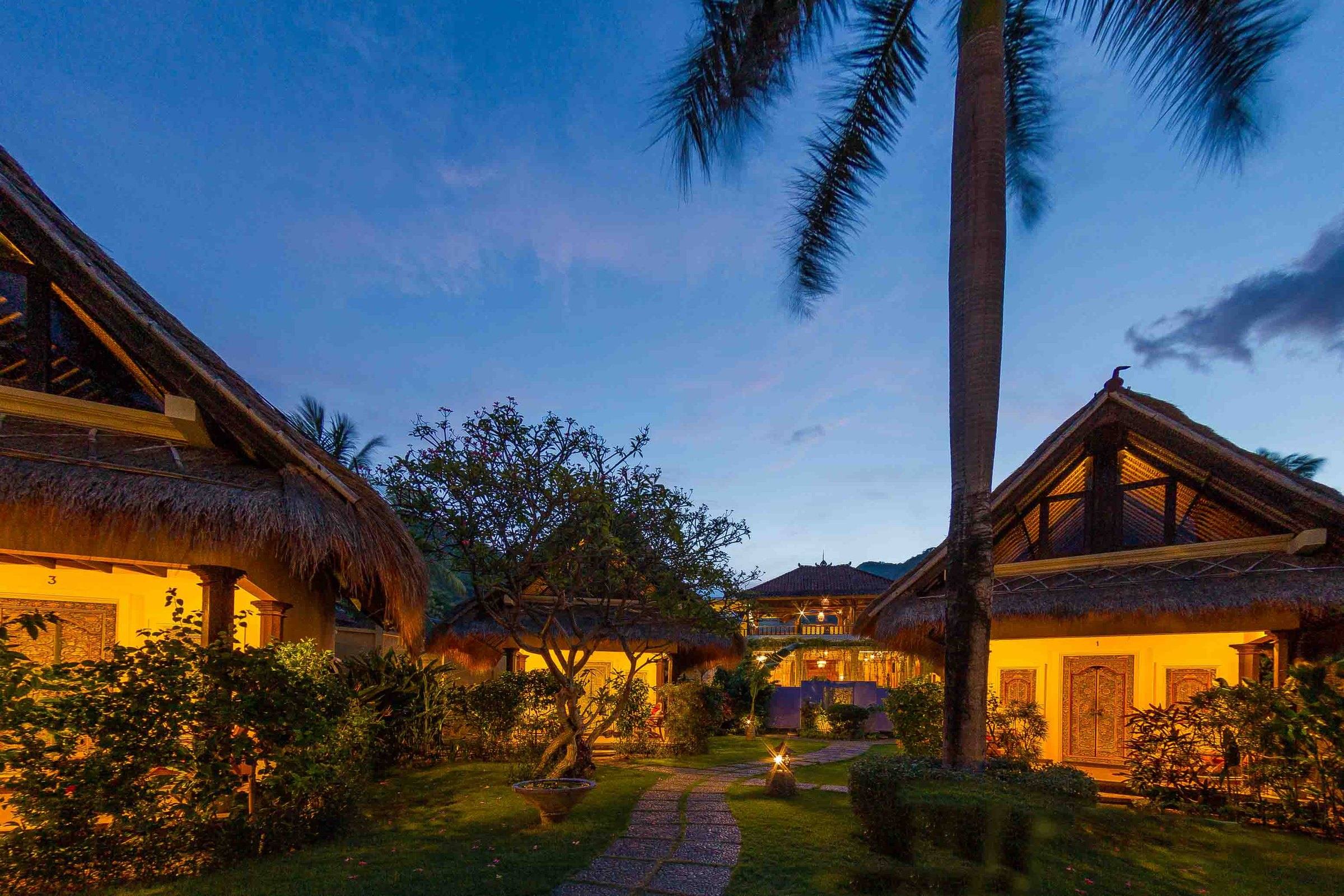 Thatched cottages glowing in the garden at dusk