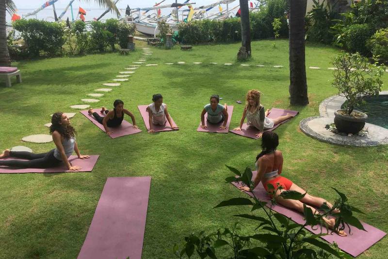 A group practising yoga on the lawn by the beach