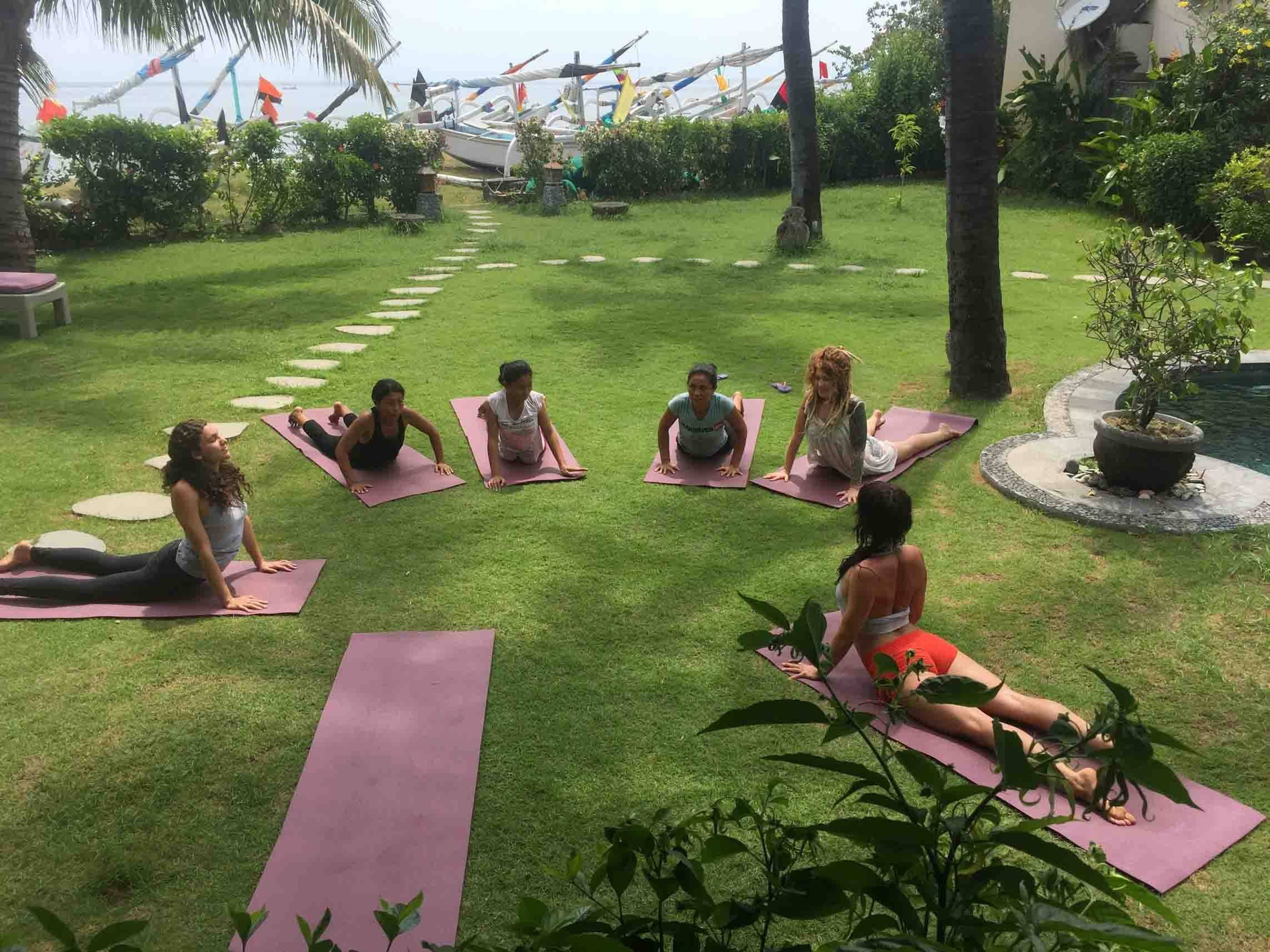 A group practising yoga on the lawn by the beach