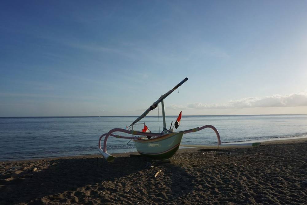 A traditional jukung fishing boat on the beach at dawn in Amed