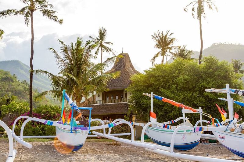 Colourful jukung boats resting on the sand in front of the hotel garden