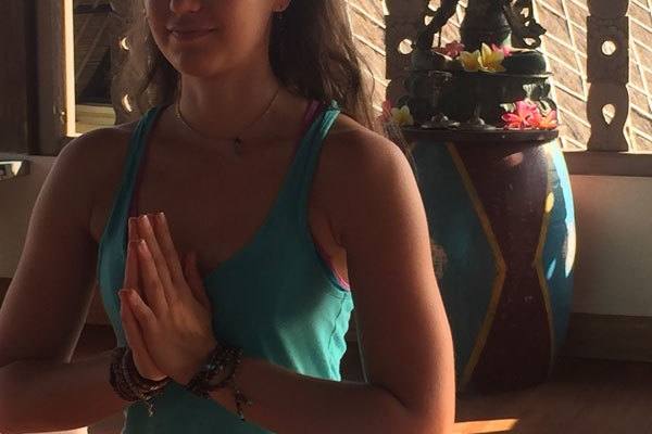 A woman meditating with hands in prayer position in the shala