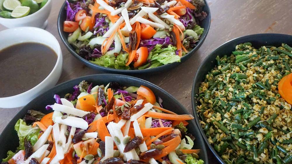 Colourful organic salads and a vegetable dish served family-style