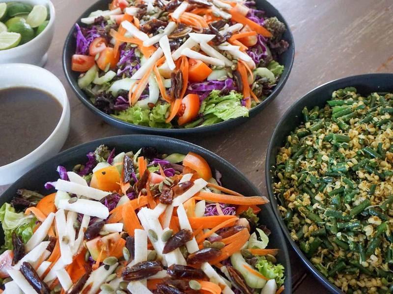 Colourful organic salads and a vegetable dish served family-style