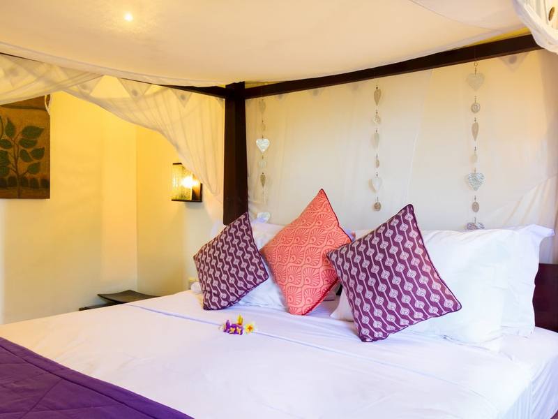 White canopy bed with purple and pink cushions in Paradiso Villa