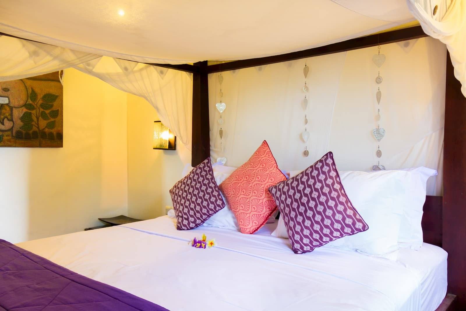 White canopy bed with purple and pink cushions in Paradiso Villa