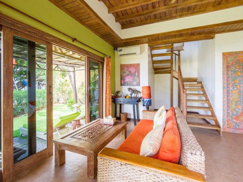 Paradiso Villa living room with orange sofa and stairs to the loft