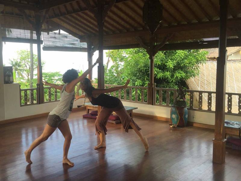 Two people practising a flowing partner yoga sequence in the shala