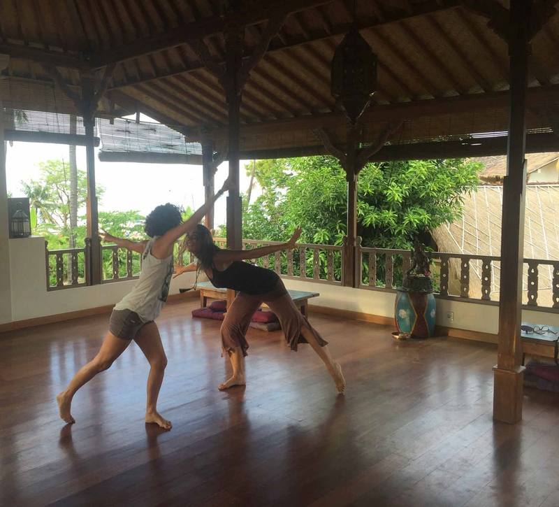 Two people practising a flowing partner yoga sequence in the shala