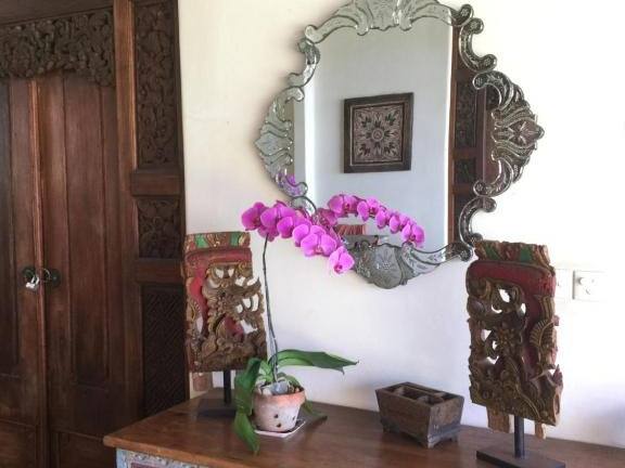 Antique carved chest, mirror and orchids in the Perfumed Garden