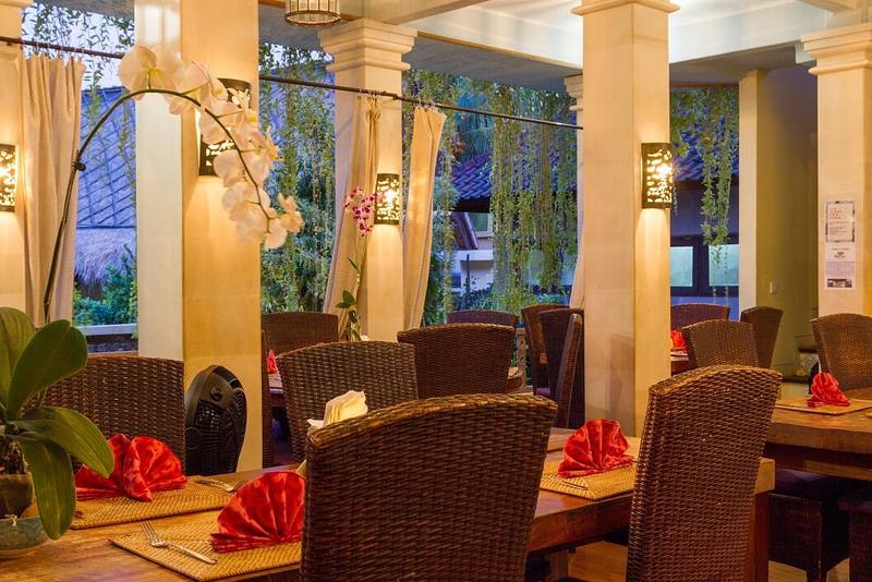 Restaurant tables set with red napkins and orchids
