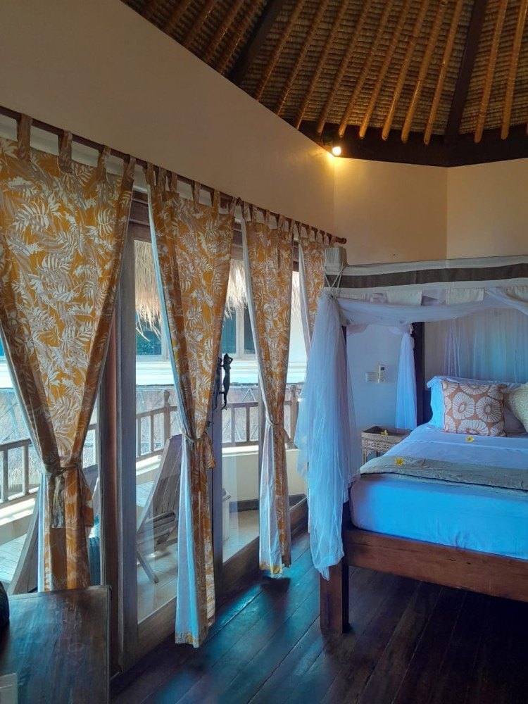 Four-poster bed in the upstairs bedroom of Sari Sunrise Villa with curtains open