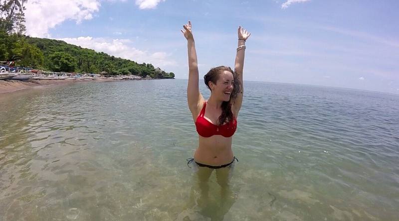 A smiling guest in the calm clear water in front of the hotel, ready to snorkel