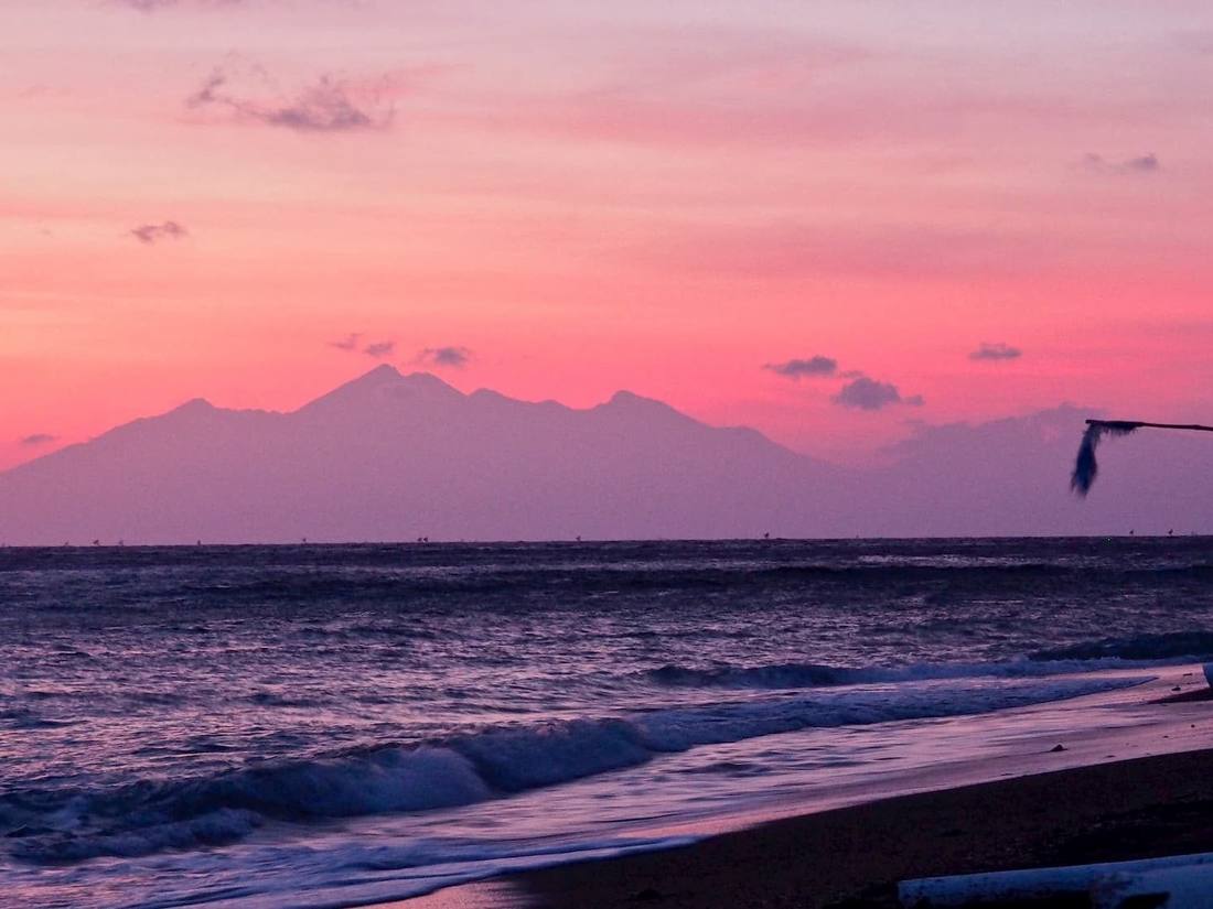 Pink sunrise over the sea with the silhouette of Mount Rinjani on Lombok, seen from the beach at Life in Amed