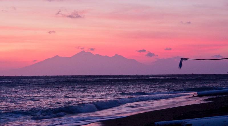 Pink sunrise over the sea with the silhouette of Mount Rinjani on Lombok, seen from the beach at Life in Amed