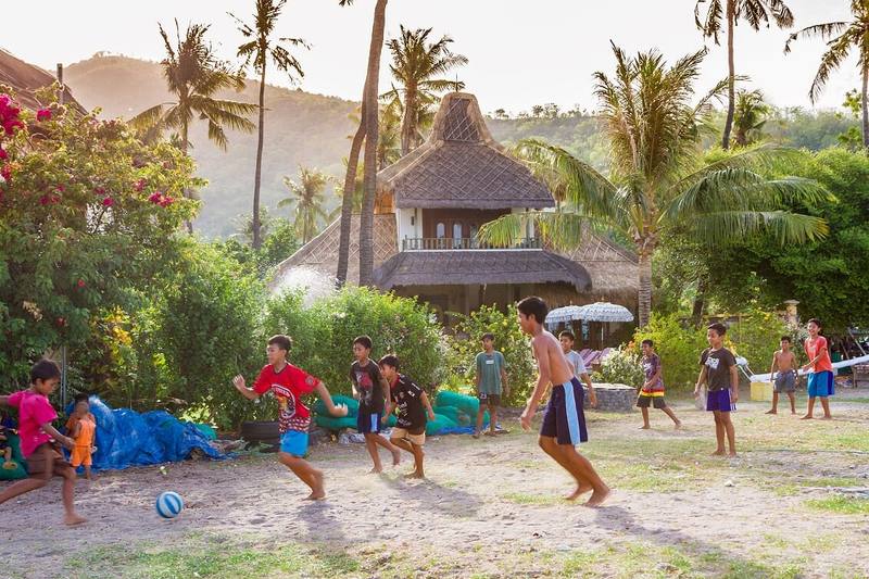 Children from Lean village playing football on the beach in front of the jukung boats