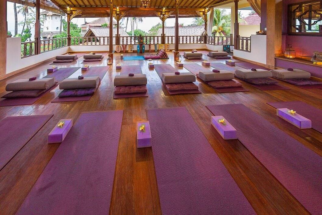 Yoga mats, bolsters and blocks laid out in the shala in the morning light